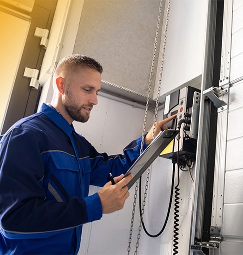 Technicien Chronoserve effectuant la maintenance préventive d'un rideau métallique à Paris, graissage de l'axe.