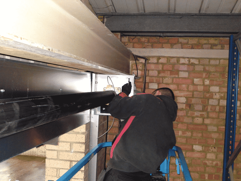 Technicien installant un nouveau moteur tubulaire pour le changement moteur d'un rideau métallique à Paris